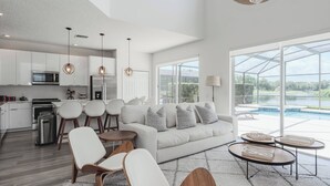 A modern kitchen with white cabinets, stainless steel appliances, and pendant lighting. - Family Resort Pool Home Near Disney (Kissimmee)
