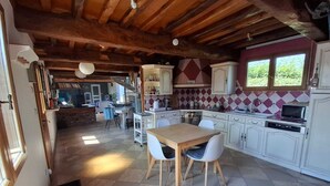 A spacious kitchen with a dining area, wooden ceiling beams, and a view of the outdoors. - A family home between the sea and the countryside! (Sainte-Agathe-d'Aliermont)