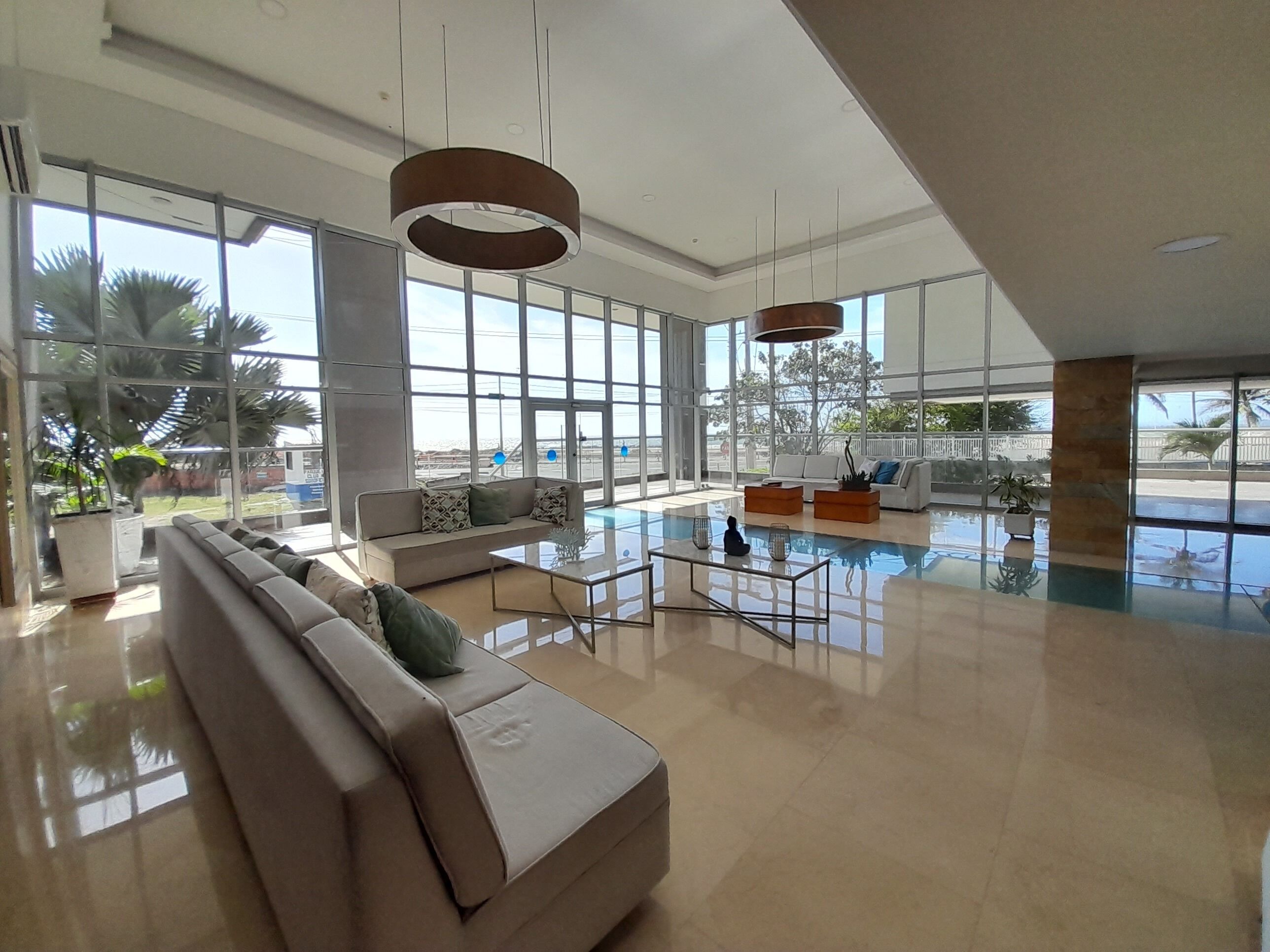 A spacious lobby with a large window, a seating area with a sofa and armchairs, and a central coffee table.