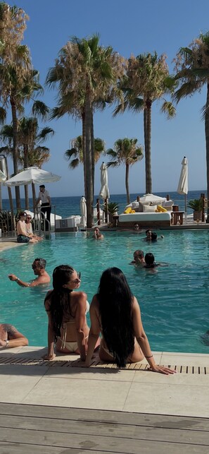 A pool area with lounge chairs, umbrellas, and palm trees. - Wonderful Studio Loft with Ocean View (Marbella)