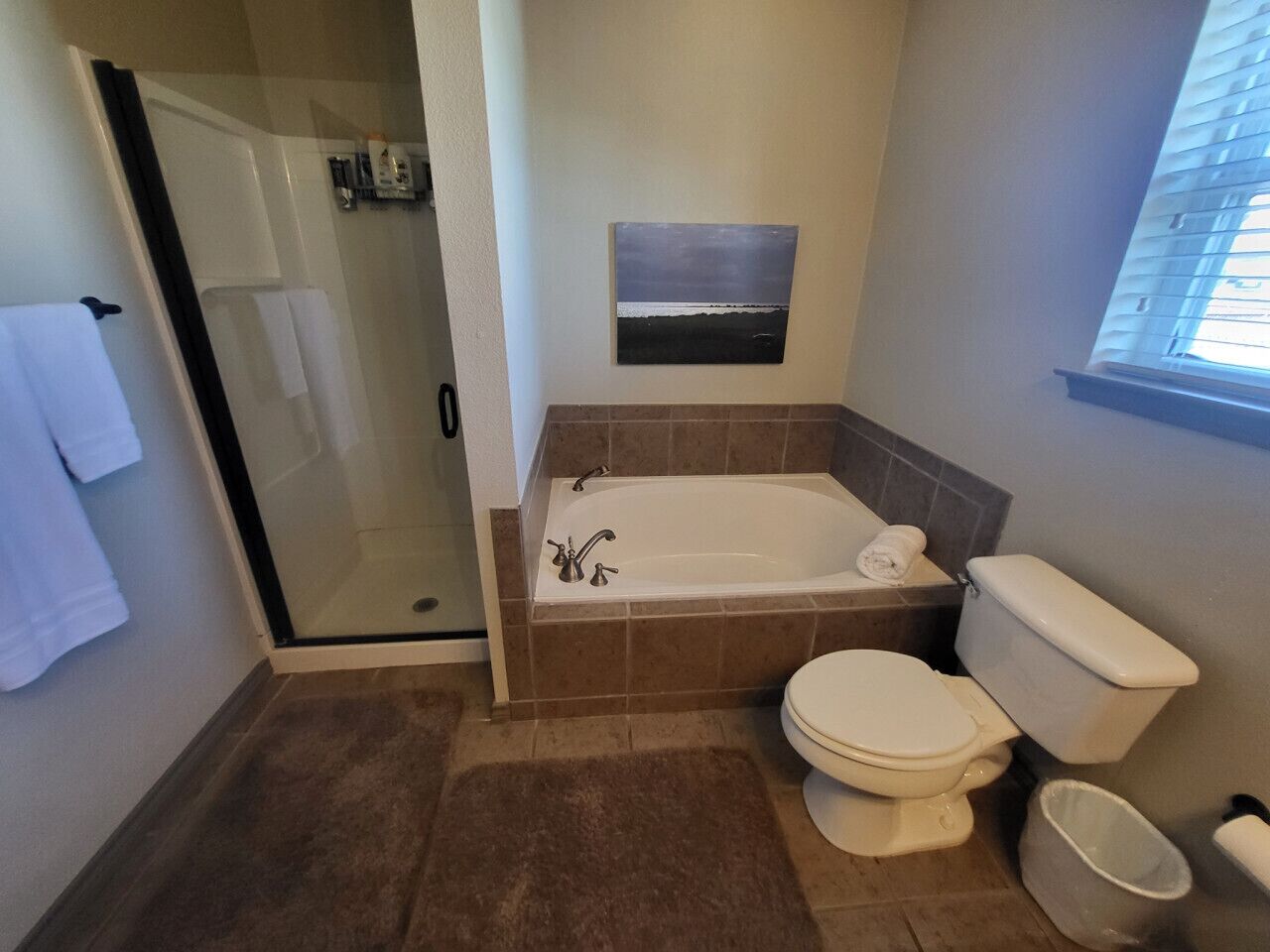 Un baño con cabina de ducha de vidrio, bañera y retrete.