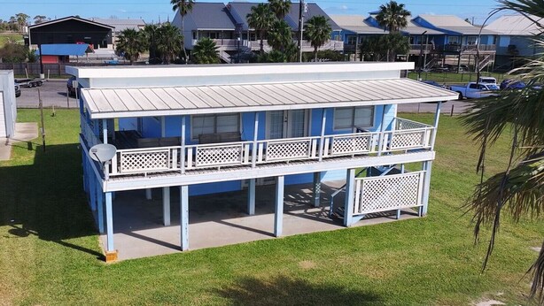 A two-story building with a balcony, a garage, and a grassy yard. - Waterview House by the Public Boat Ramp (Port O`Connor)