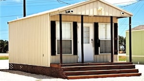 A small, single-story building with a front porch, a door, and two windows.
