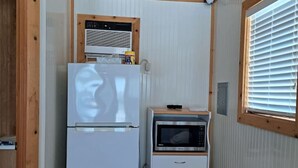 A compact kitchen with a refrigerator, microwave, and a small cabinet.