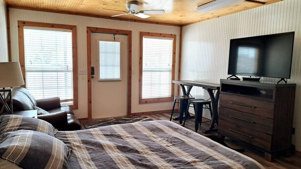 A bedroom with a bed, a desk, a TV, and a chair.