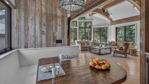 Un vaste espace de vie comprenant une table à manger en bois, un ensemble de canapés et une grande fenêtre donnant sur l’extérieur.