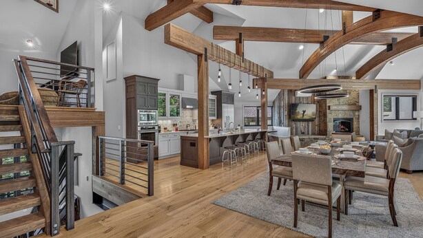 Une cuisine spacieuse équipée d’appareils modernes, un coin repas avec une grande table et des chaises, et un escalier doté d’une rampe en métal.