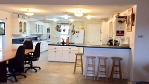 A kitchen with white cabinets, a wooden dining table with chairs, and a bar area with stools. - Beautiful Intracoastal Home with Two Boat Lifts and a Boat Slip (Port O`Connor)