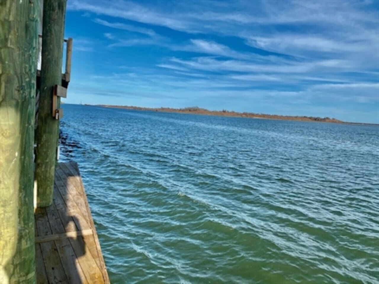 A wooden pier extending into a body of water with a clear sky above.