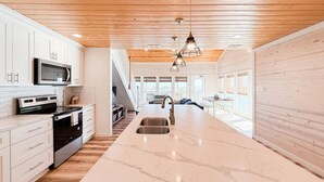 Uma cozinha moderna com uma ilha central, eletrodomésticos de aço inoxidável e teto de madeira.