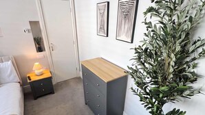 Una camera da letto moderna con un letto, un comodino, una lampada, una cassettiera e una pianta in vaso.
