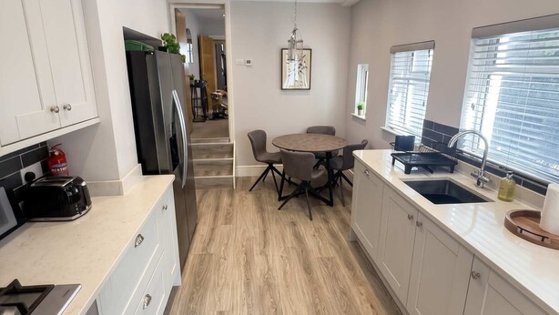 Una cucina moderna con zona pranzo, pavimento in legno e vista sulla città attraverso ampie finestre.