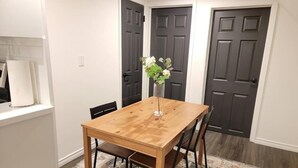 A dining area with a wooden table and chairs, a vase with flowers, and dark doors in the background. - 2br, Welland Canal, Near Merritt, 20 Min To Falls (Welland)