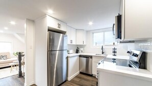 Eine moderne Küche mit Edelstahlgeräten, weißen Schränken und Holzboden.
