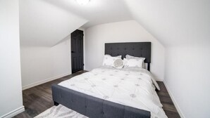 Ein Schlafzimmer mit einem Bett, einem dunklen Kopfteil und einer Deckenleuchte.