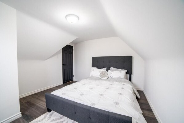 Ein Schlafzimmer mit einem Bett, einem dunklen Kopfteil und einer Deckenleuchte.