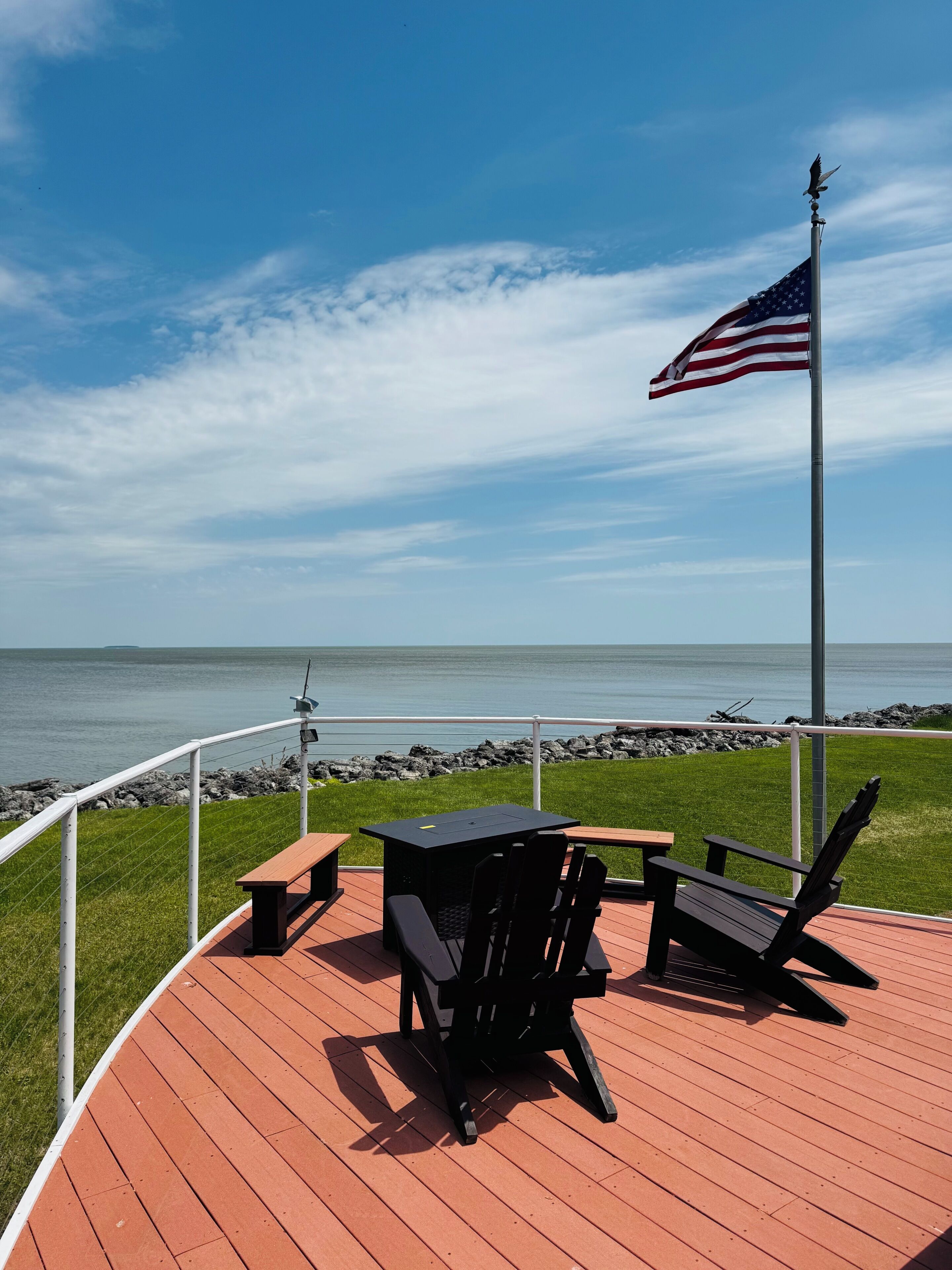 Eine Terrasse mit Tisch und Stühlen, eine amerikanische Flagge und Blick auf den Ozean.