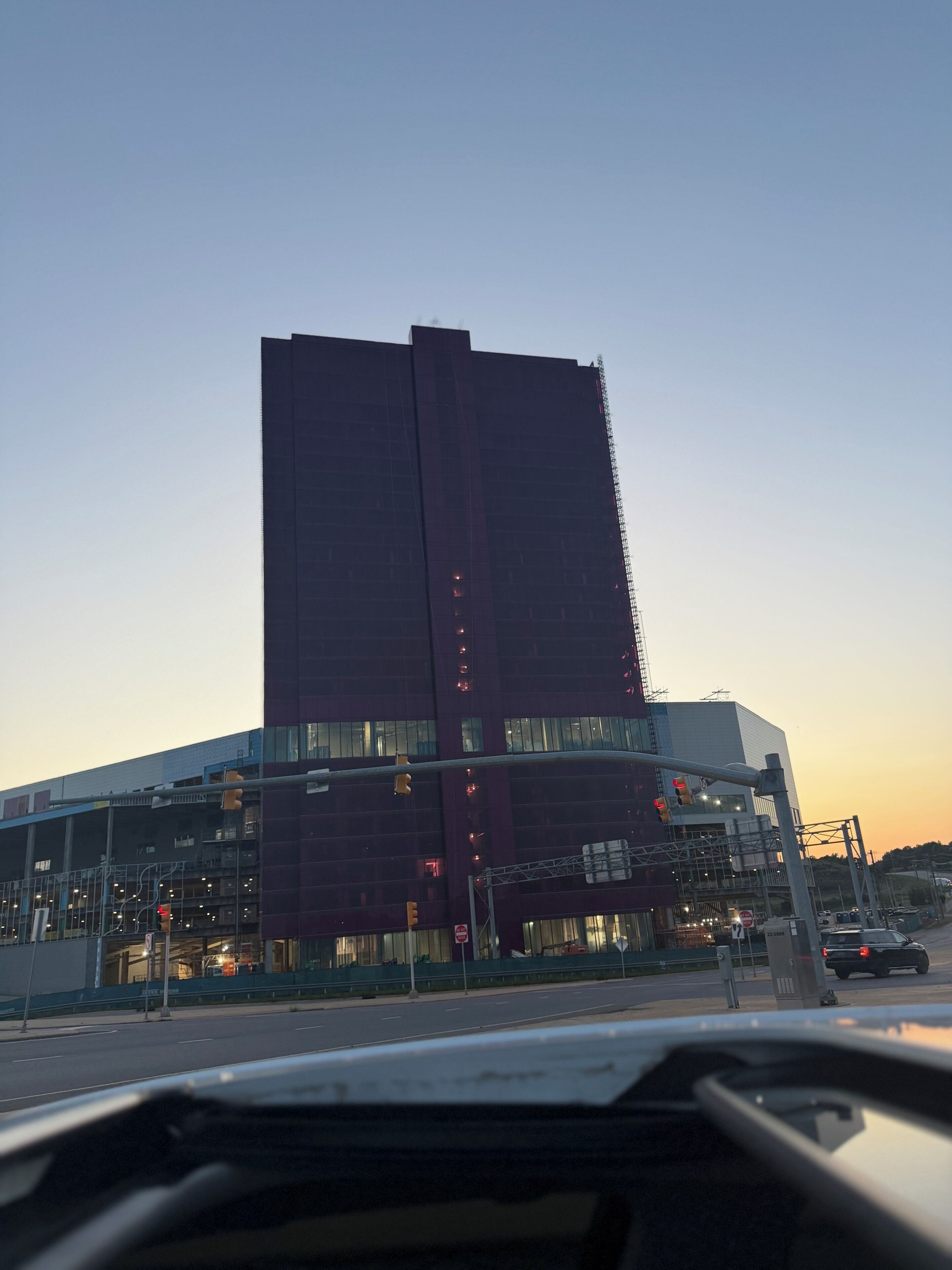 A tall building with a modern design, a traffic light, and a street in the foreground.