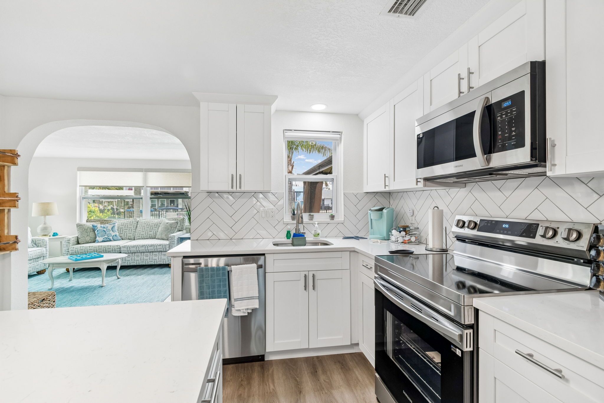 A modern kitchen with white cabinets, a built-in microwave, and an oven.