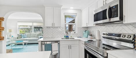 A modern kitchen with white cabinets, a built-in microwave, and an oven.