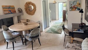 A dining area with a round table, two chairs, a fireplace, and a hallway leading to another room. - Villa Cap d'Antibes, a 2-minute walk from the beaches. (Antibes)