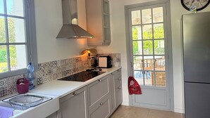 A kitchen with a large window, a hanging light fixture, a built-in oven, and a refrigerator. - Villa Cap d'Antibes, a 2-minute walk from the beaches. (Antibes)