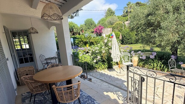 A covered patio with a round table and wicker chairs, a stone pathway, and a garden with various plants and a pergola. - Villa Cap d'Antibes, a 2-minute walk from the beaches. (Antibes)
