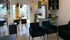 Moderni keittiö, jossa on jääkaappi, liesi sekä ruokailutila, jossa on tuoleja ja pöytä.