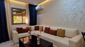 A modern living room with a sofa, a coffee table, and a decorative light fixture. - 
Apartment cosy modern and luxury Marrakech (Marrakesh)