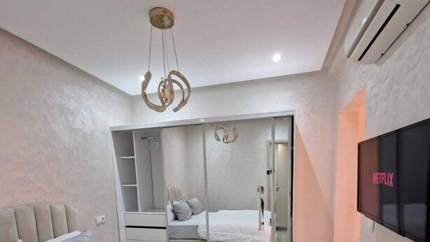 A bedroom with a bed, a wardrobe, a TV, and an air conditioning unit. - 
Apartment cosy modern and luxury Marrakech (Marrakesh)