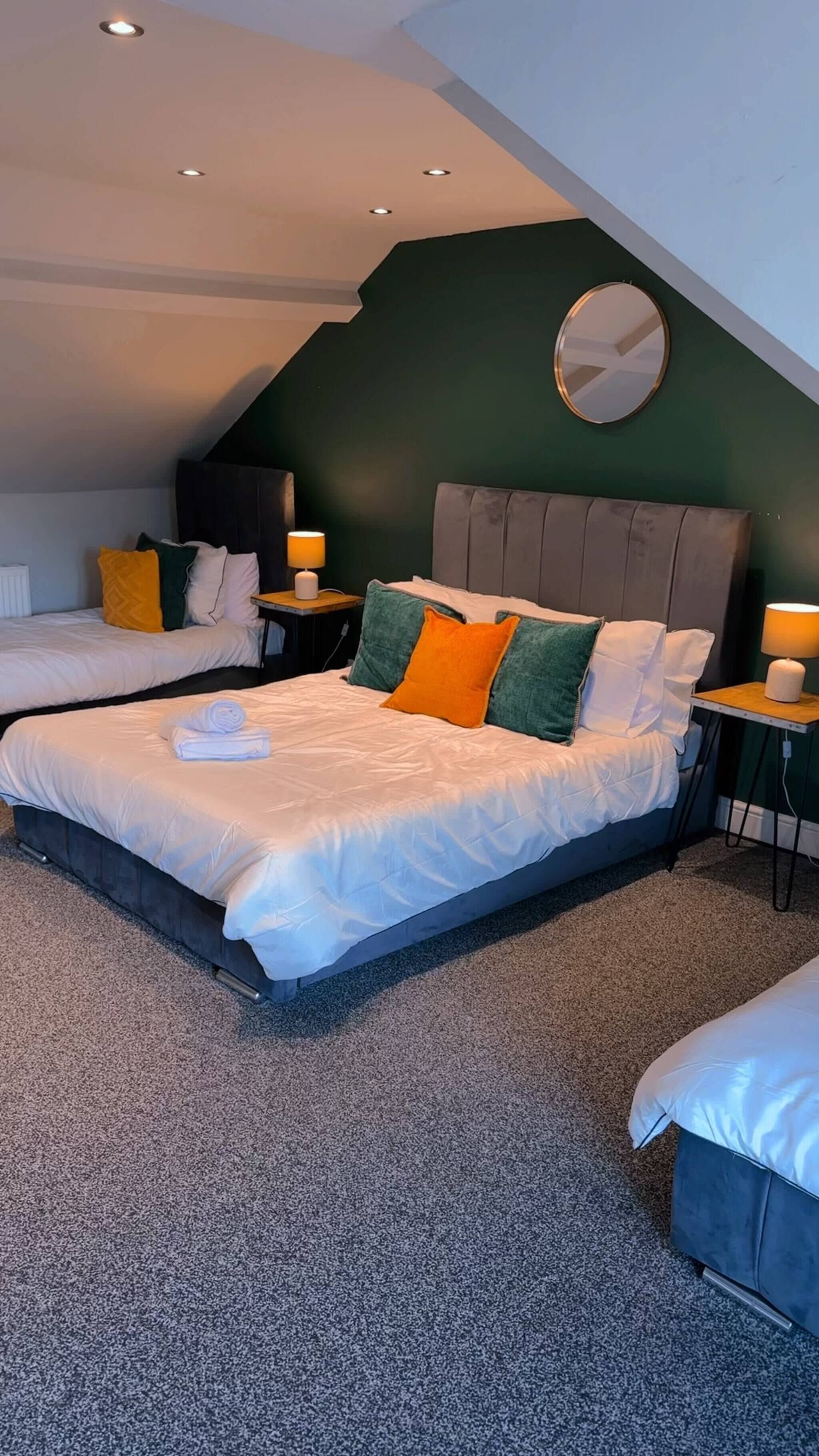 A hotel room with two beds, a round mirror, and a ceiling with recessed lighting.