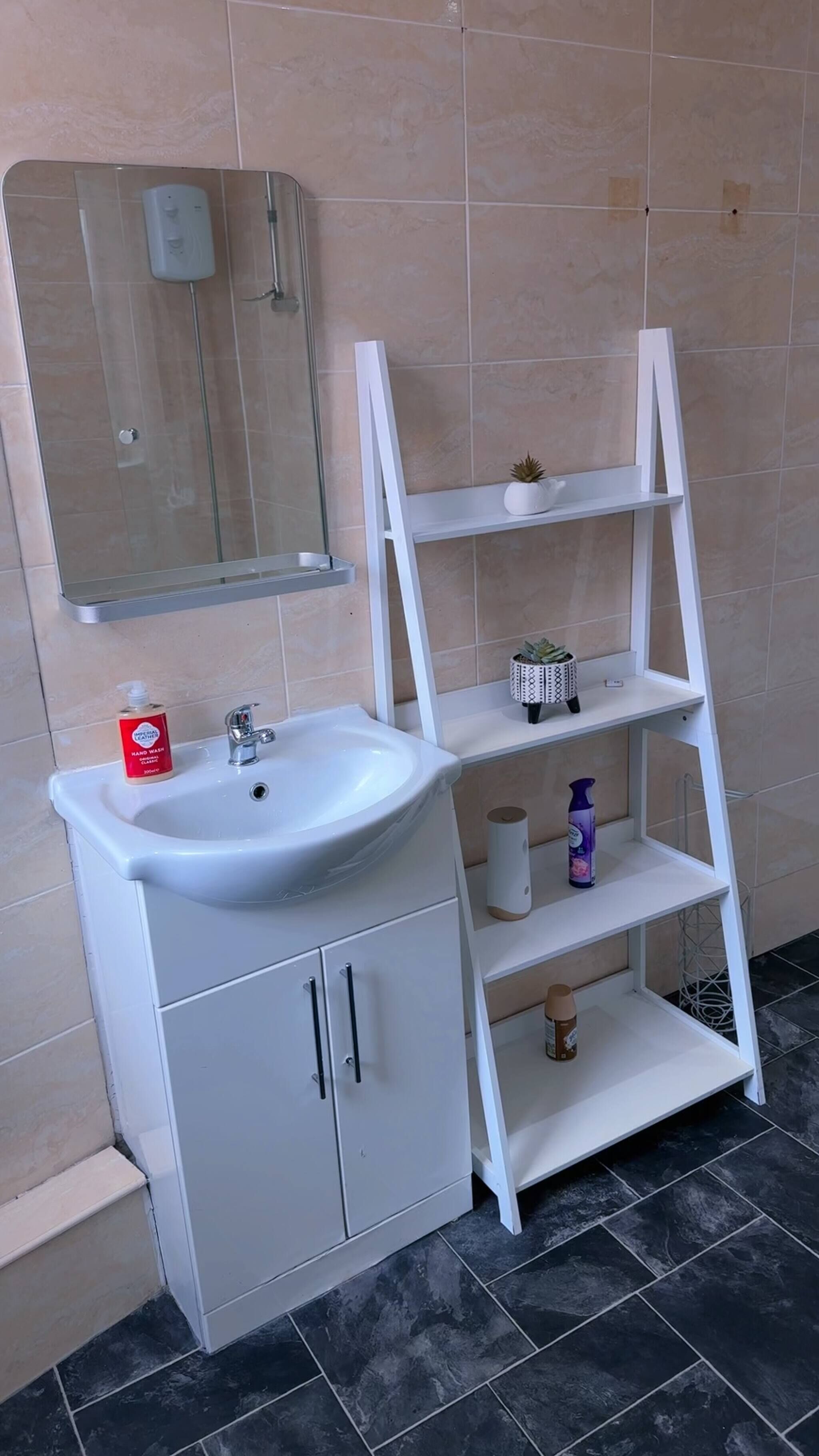 Ein Badezimmer mit Waschbecken, Spiegel und Regalen.