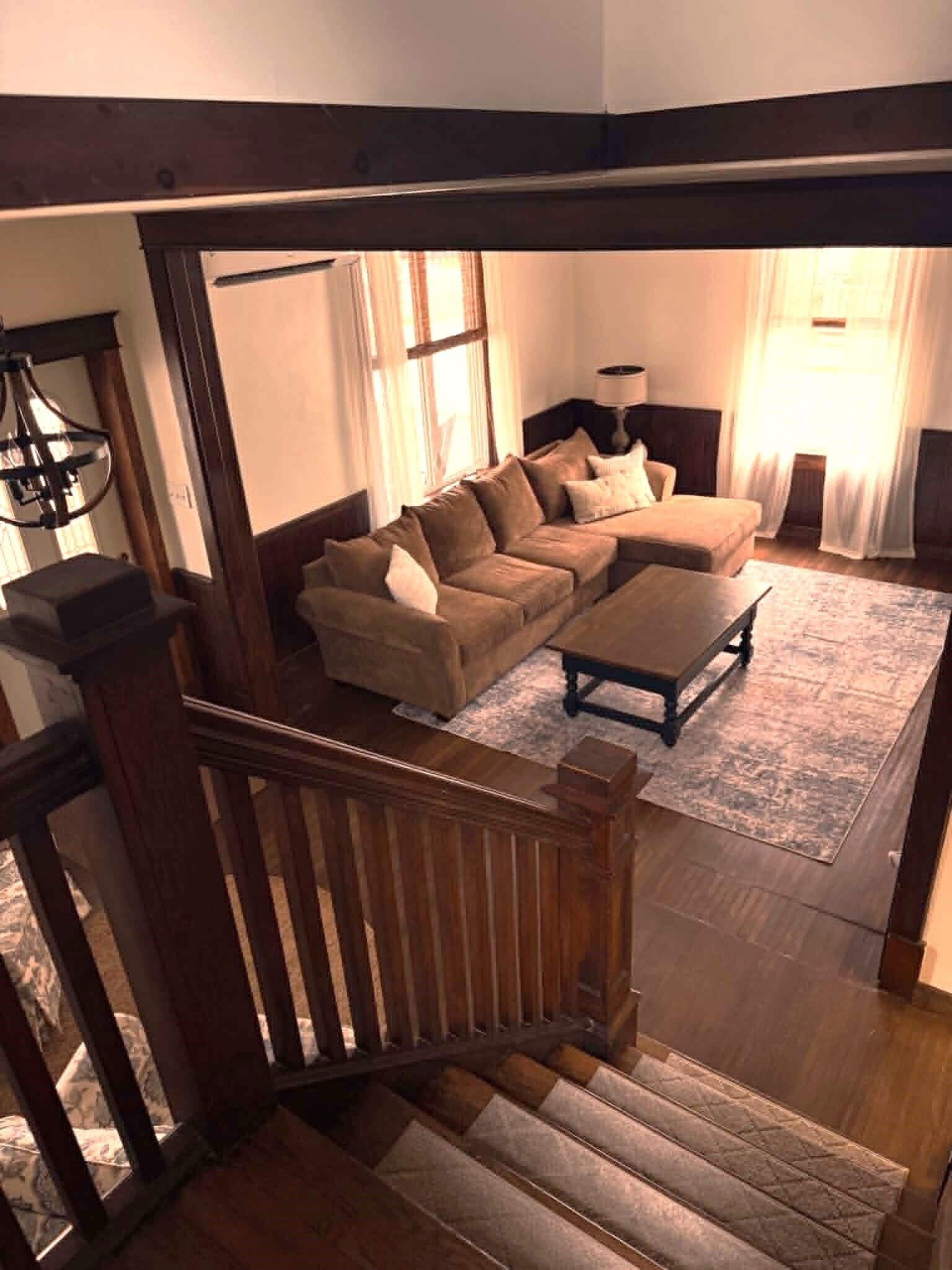 Eine Treppe führt zu einem Wohnzimmer mit einer Couch, einem Couchtisch und einer Lampe.