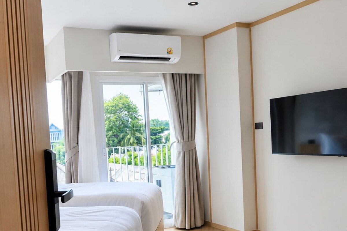 Habitación de hotel con cama, aire acondicionado, televisión y vistas a zonas verdes.