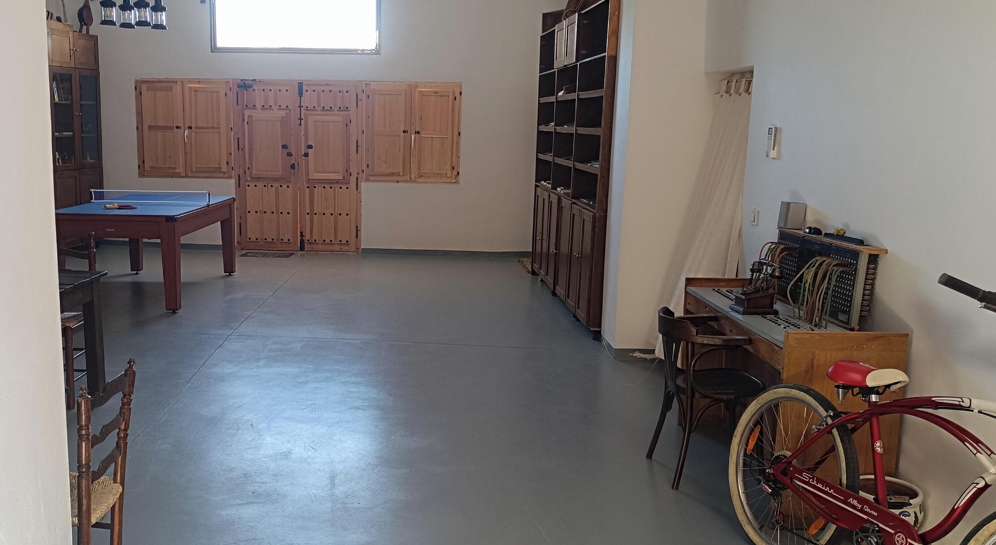 Una habitación con mesa de billar, armarios de madera, una bicicleta y un escritorio con computadora.