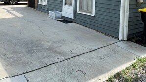 A two-story residential building with a garage door, a car parked inside, and a small trash bin outside. - 2-bedroom apartment 0.1miles from Forsyth Park, steps from Kroger and parking.  (Savannah)