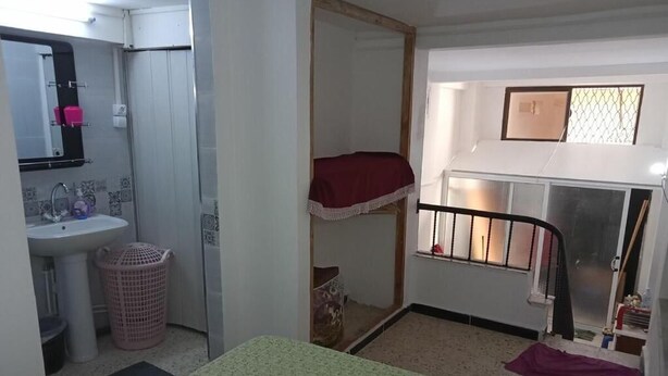 Ein Zimmer mit einem Etagenbett, einem kleinen Fenster, einem Waschbecken und einem Spiegel.