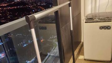 Un balcon doté d’une structure métallique, d’une rambarde en verre et offrant une vue sur le paysage urbain illuminé la nuit.