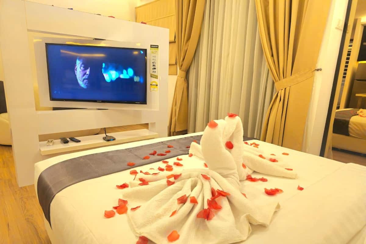 A hotel room with a bed, a TV, and curtains.