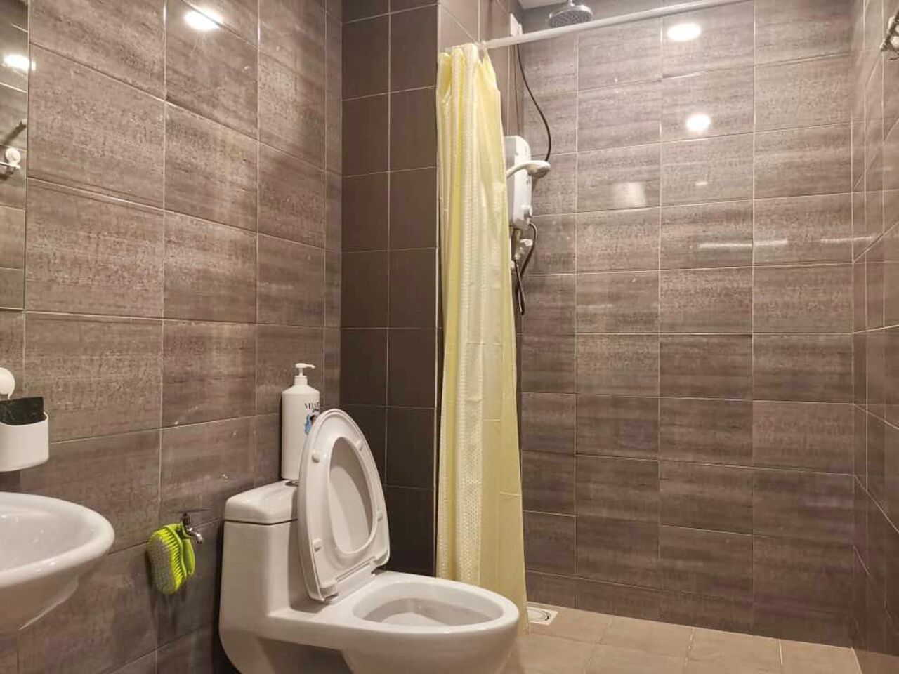 A bathroom with a toilet, sink, and shower area.