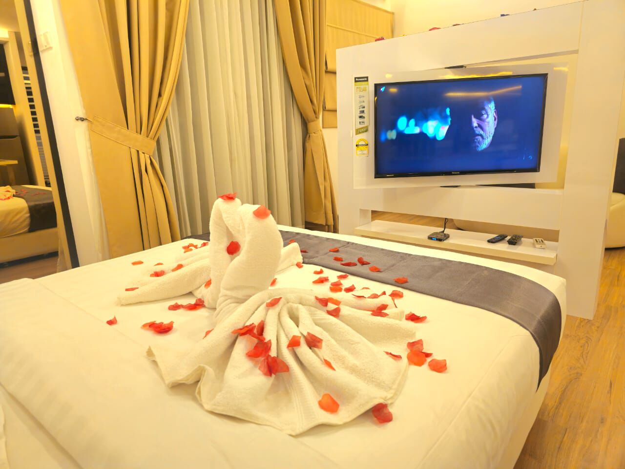 A hotel room with a bed, a television, and curtains.
