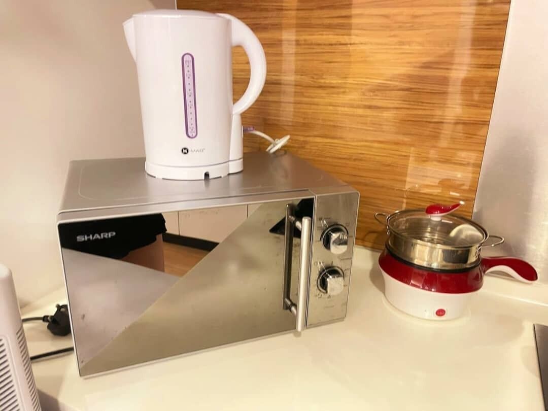 A kitchen with a coffee maker, a pot, and a microwave.
