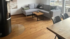 En moderne stue med træloft, en grå sofa, et sofabord og et spisebord.