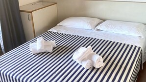 A hotel room with a bed, two pillows, a bedside table, and two rolled towels. - P.Rotondo1 M131 Two-Bedroom Apartment 5 SEA VIEW (Porto Rotondo)