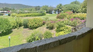 A garden with various plants and flowers, a pathway, and a view of the surrounding landscape. - P.Rotondo1 M131 Two-Bedroom Apartment 5 SEA VIEW (Porto Rotondo)