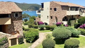 A coastal hotel with stone and stucco buildings, a paved courtyard, and a view of the sea. - P.Rotondo1 M131 Two-Bedroom Apartment 5 SEA VIEW (Porto Rotondo)
