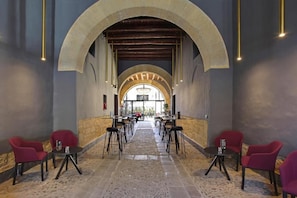 A corridor with tables and chairs, an arched ceiling, and a view through the arch. - Palazzo Corselli b&b (Bagheria)