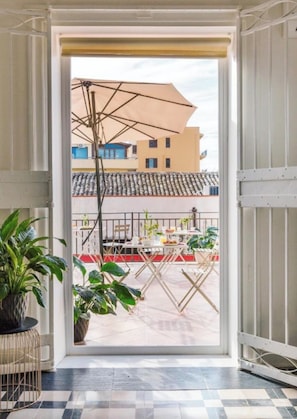 An open doorway leading to an outdoor terrace with a table, chairs, and potted plants. - Palazzo Corselli b&b (Bagheria)