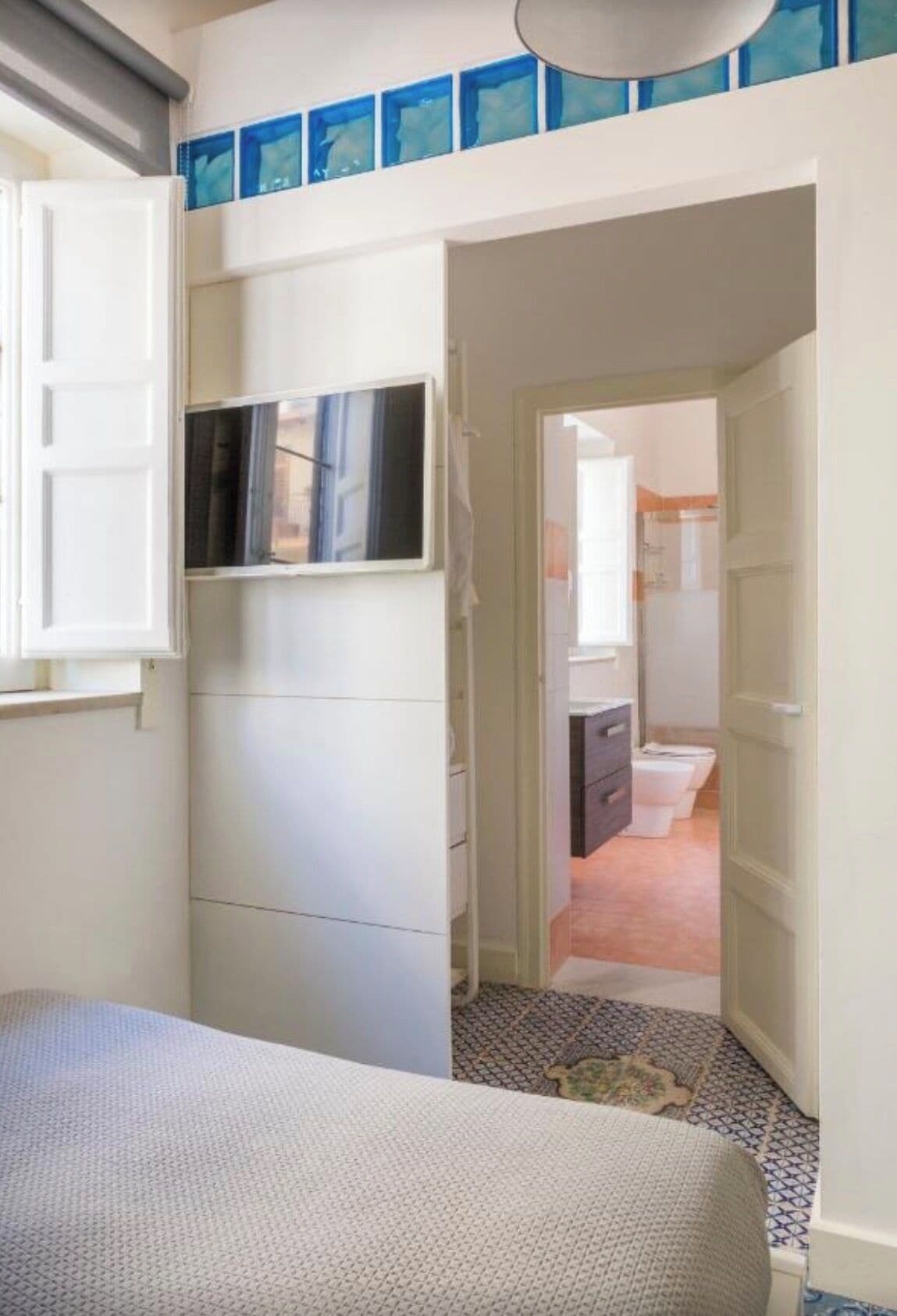 Ein Schlafzimmer mit Bett, Kleiderschrank und einer Tür zu einem Badezimmer mit Toilette und Waschbecken.