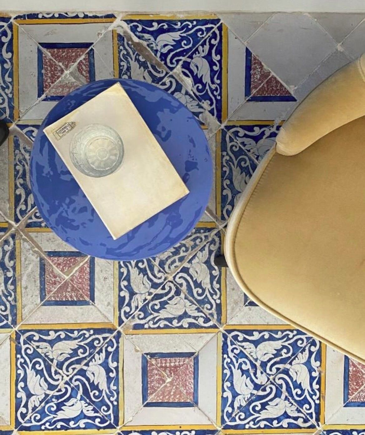 A bathroom with a blue and white patterned tile floor, a beige bathtub, and a blue sink with a white countertop.